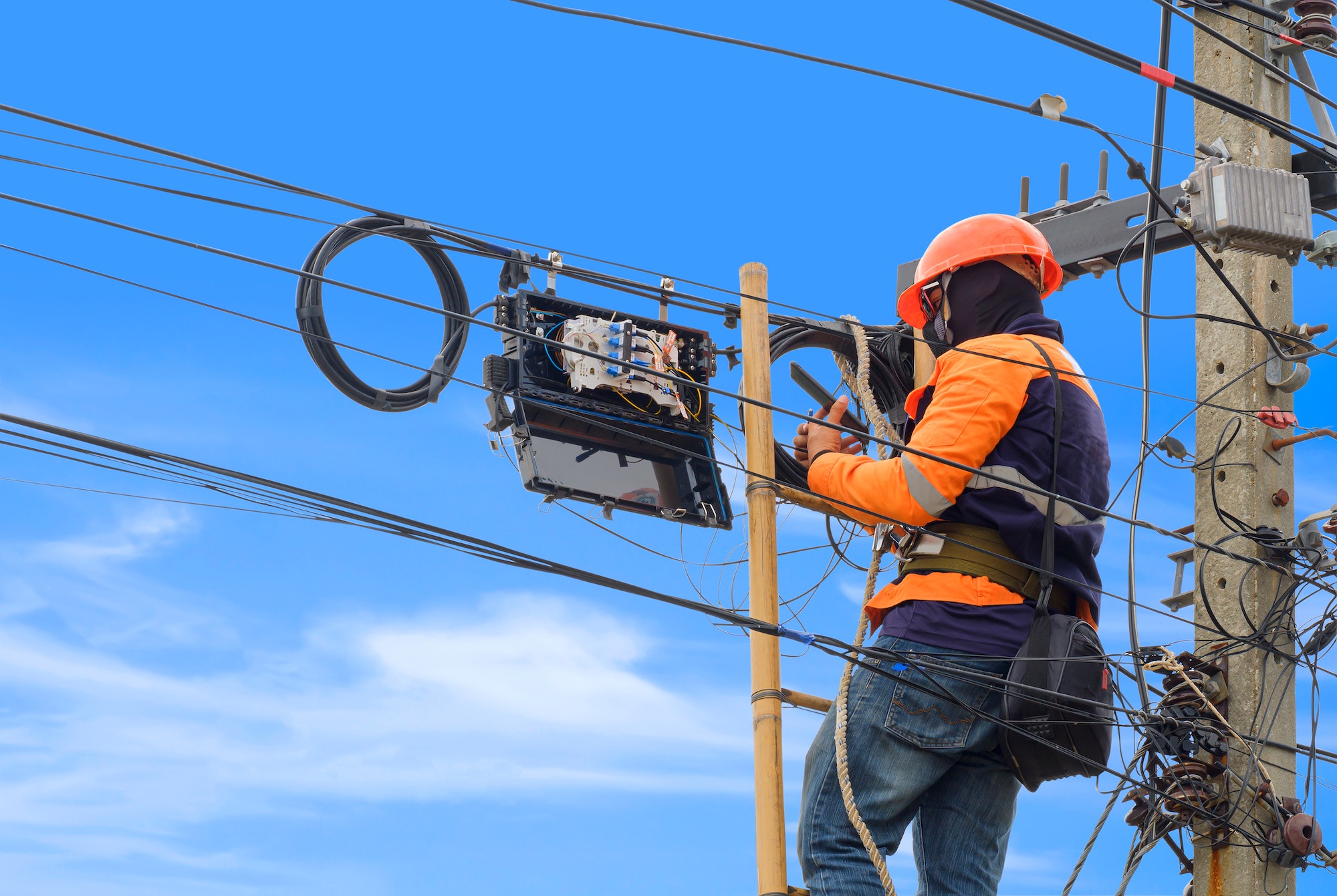 Technician using smartphone to check data of cable lines while installing fiber optic system